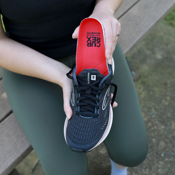 Woman placing CURREX ACTIVEPRO low profile insole into black sneaker #profile_low