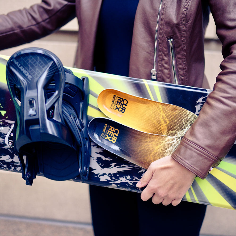 Woman holding ski board and a pair of CURREX EDGEPRO medium profile insoles #profile_medium
