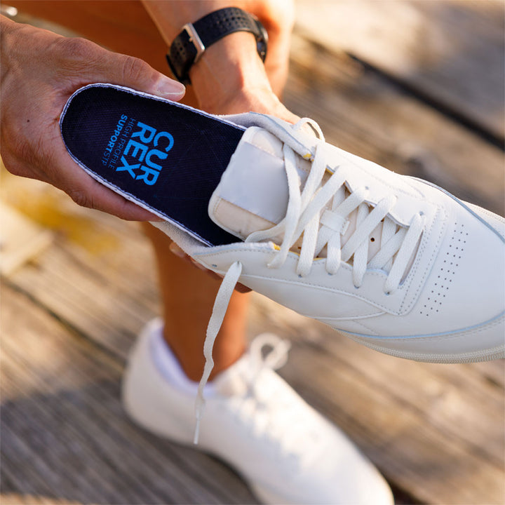 Person placing CURREX SUPPORTSTP high profile insole into white sneaker #profile_high