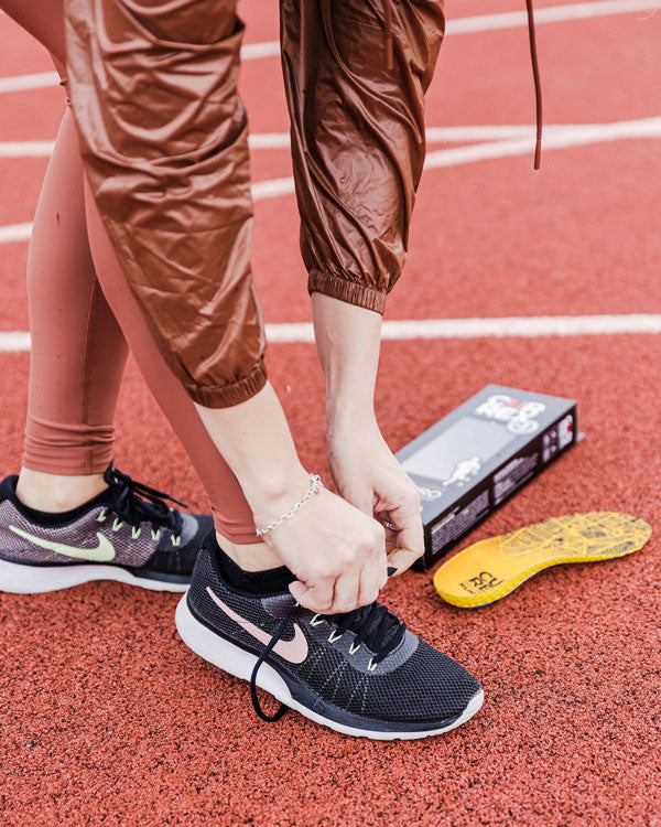 Woman tying shoe before running a lap with CURREX insoles.