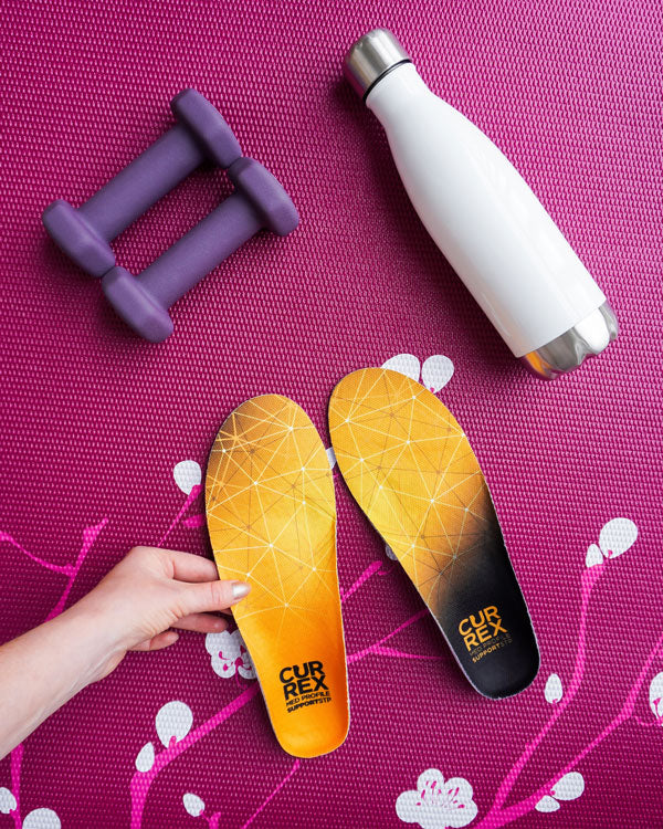 Weights, water bottle and CURREX insoles on exercise/yoga mat.