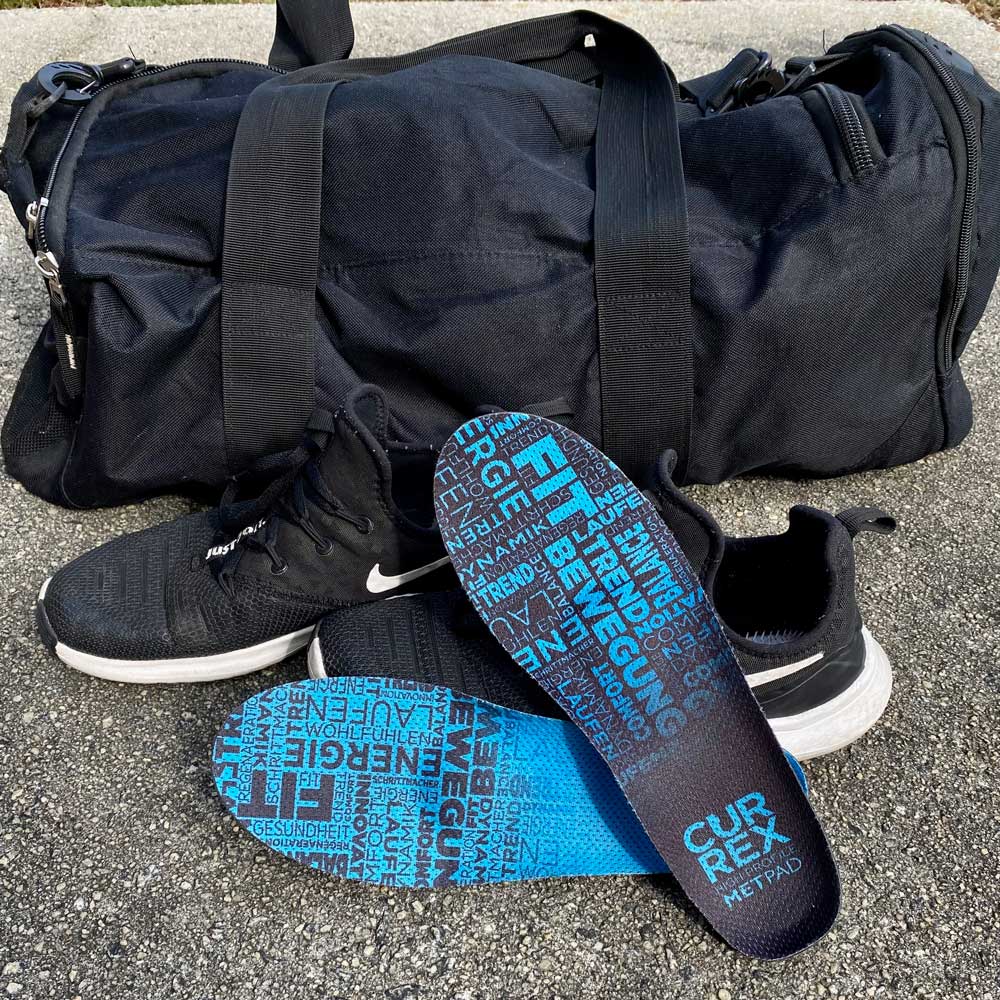 CURREX METPAD high profile insoles sitting next to black sneakers and black duffel bag #profile_low