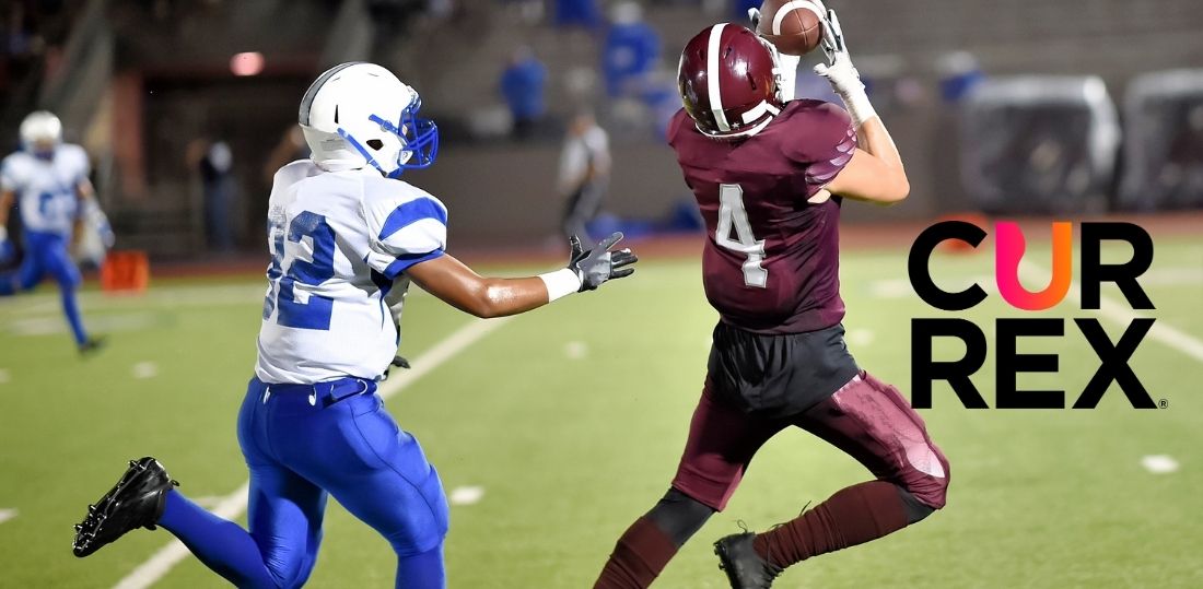 Image of a football being caught while the defender tries to tackle