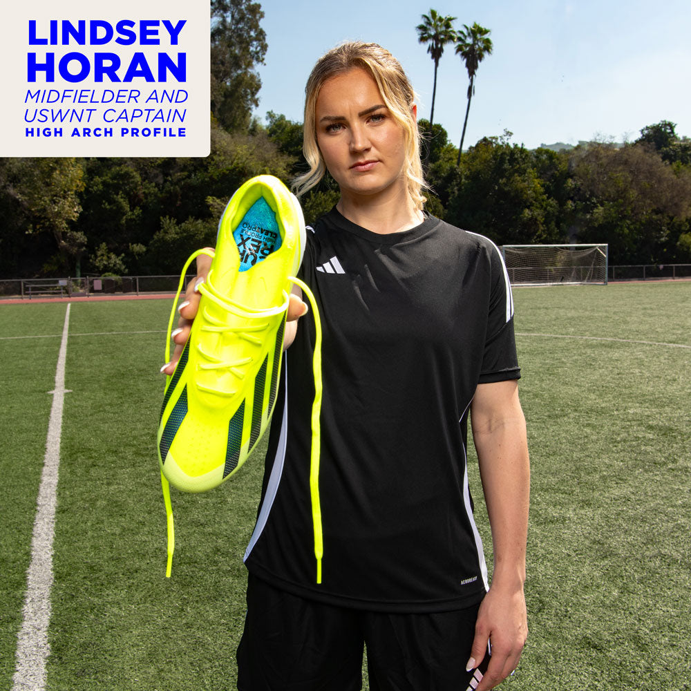 Lindsey Horan, Midfielder and USWNT Captain, uses the high profile CURREX CLEATPRO insoles. Lindsey Horan standing on soccer field, holding cleats with CURREX CLEATPRO insoles inside. #profile_low