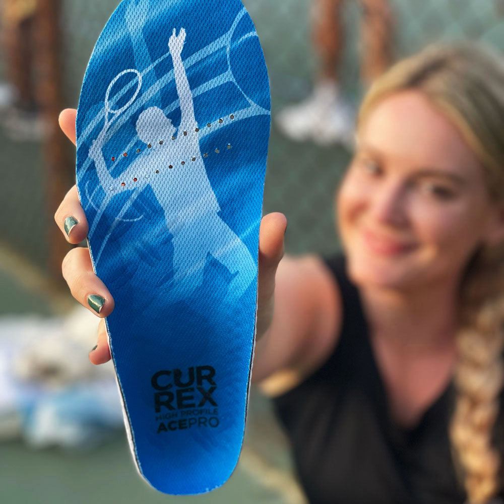 Woman holding up CURREX ACEPRO high profile insoles while at the tennis court #profile_high