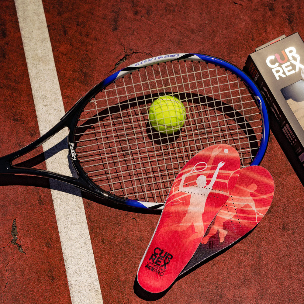 Pair of low profile CURREX ACEPRO insoles sitting on tennis court next to tennis ball and racket #profile_low