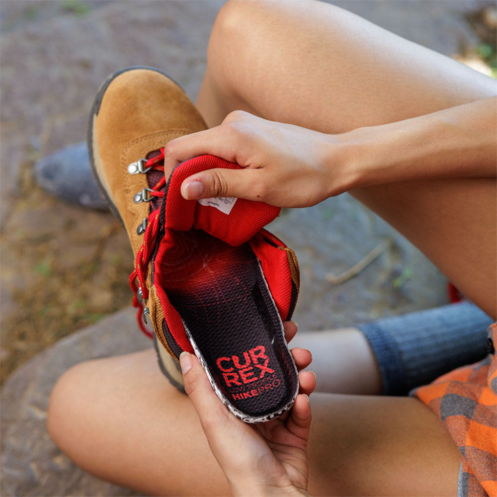 Woman placing CURREX HIKEPRO low profile insole into taupe colored hiking boot #profile_low