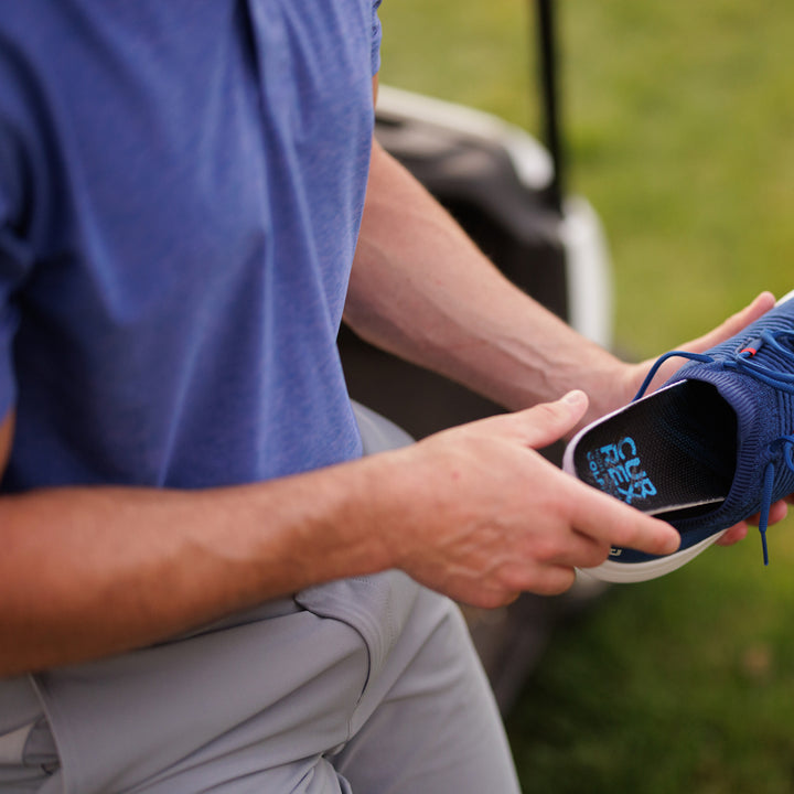 Man placing CURREX GOLFPRO insoles into shoe at the golf course #profile_low