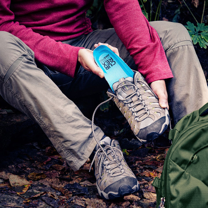 Man outside placing CURREX HIKEPRO insoles into shoe before going on the hiking trail #profile_low