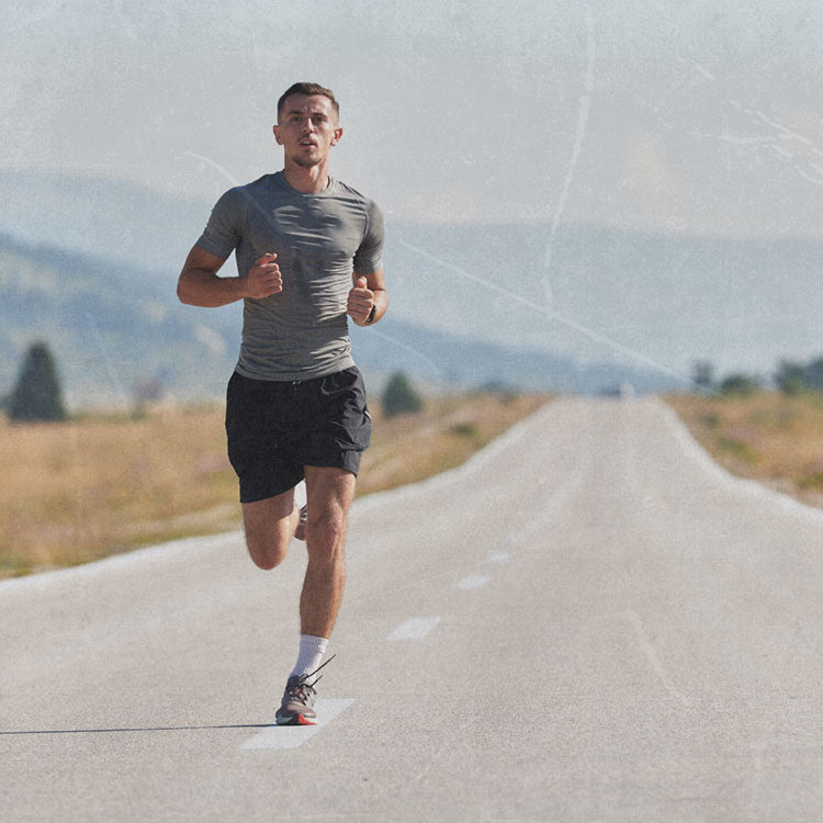 Man running on a road with mountains in the background