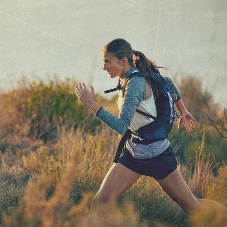 Woman running outdoors with a backpack in a natural setting