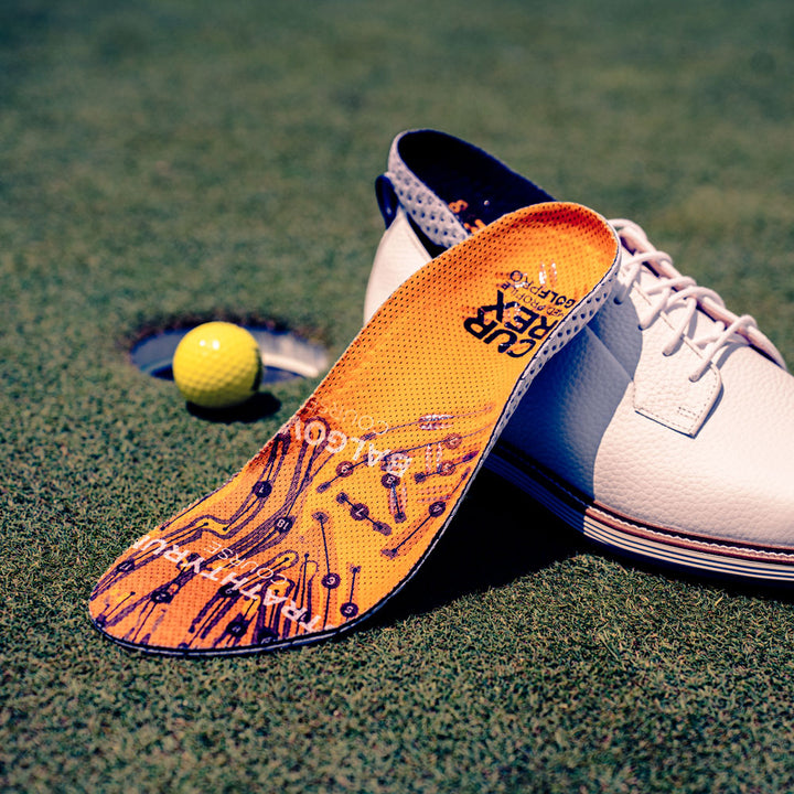 Medium profile CURREX GOLFPRO insoles sitting on golf shoe next to golf ball #profile_medium