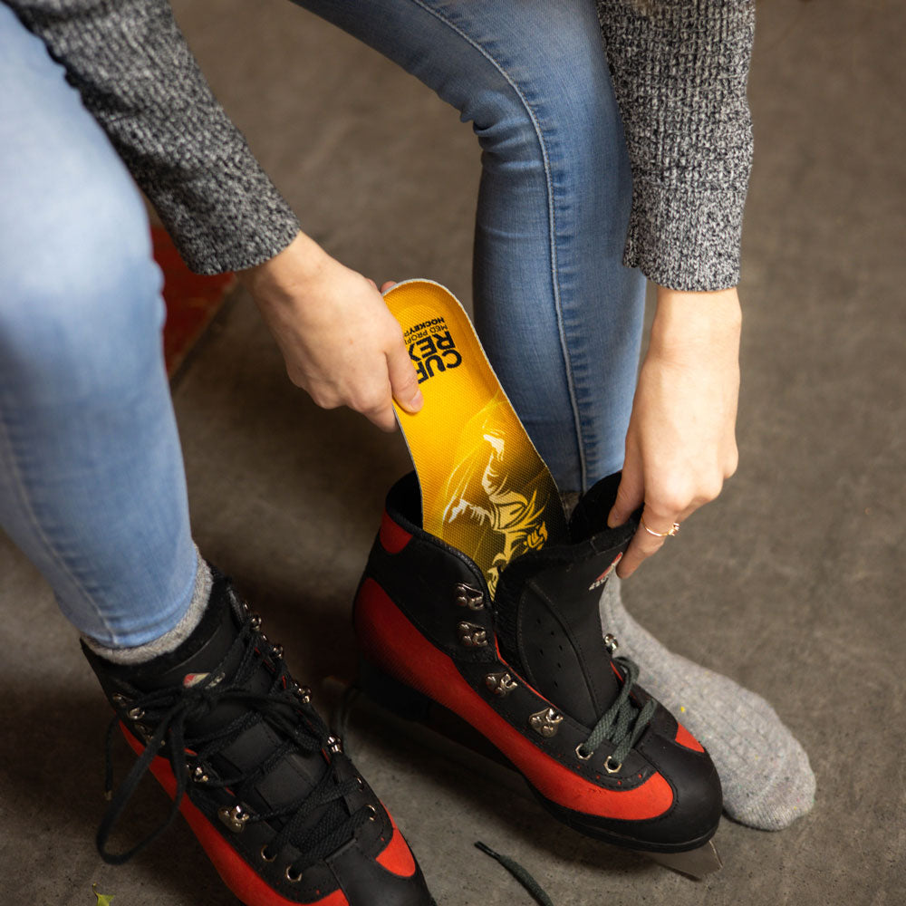 Woman placing yellow medium profile CURREX HOCKEYPRO insoles into red and black hockey skates #profile_medium