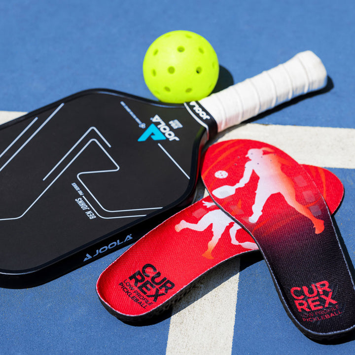 CURREX PICKLEBALLPRO red low profile insoles sitting next to pickleball gear; pickleball paddles and pickleball ball #profile_low