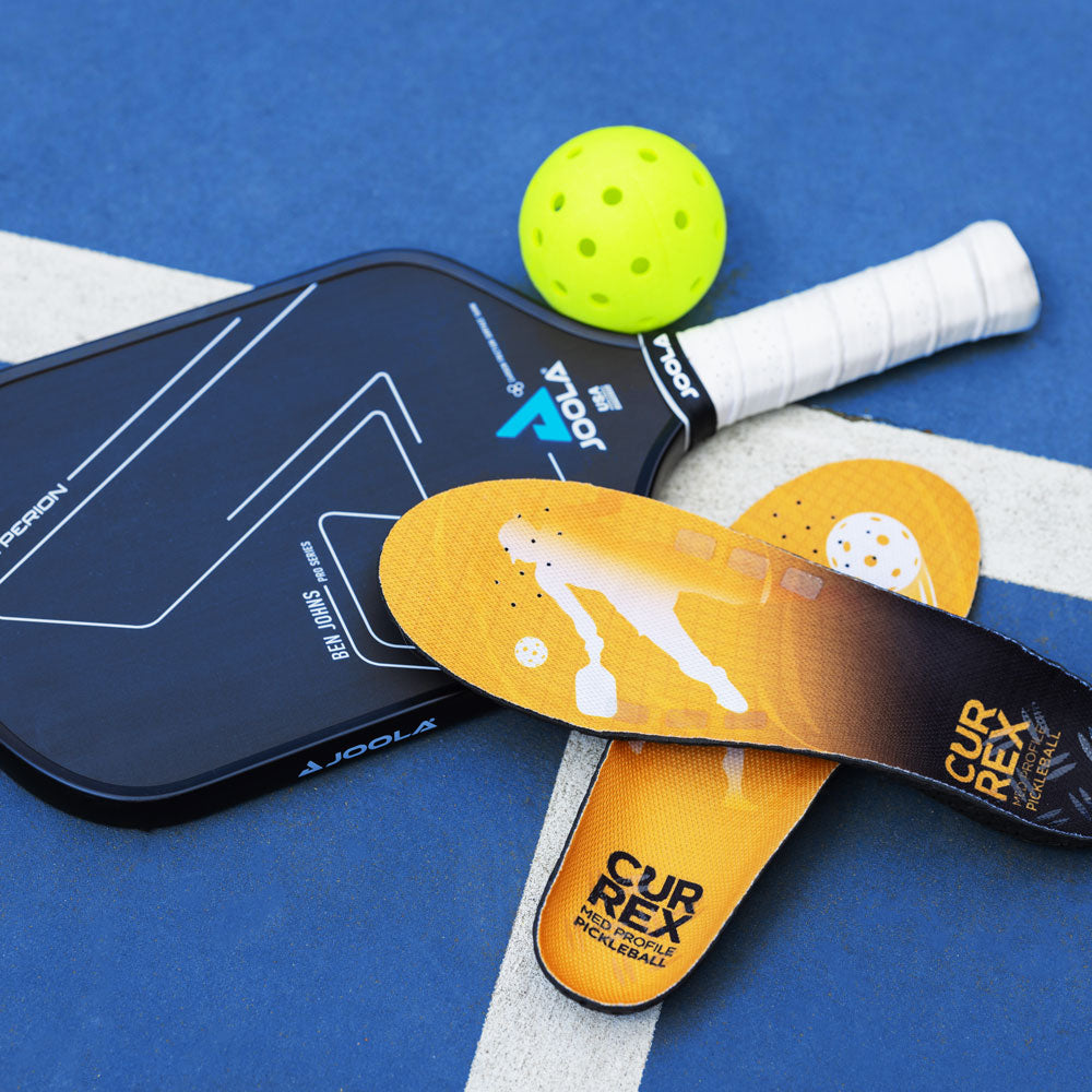 CURREX PICKLEBALLPRO yellow medium profile insoles sitting next to pickleball gear; pickleball paddles and pickleball ball #profile_medium