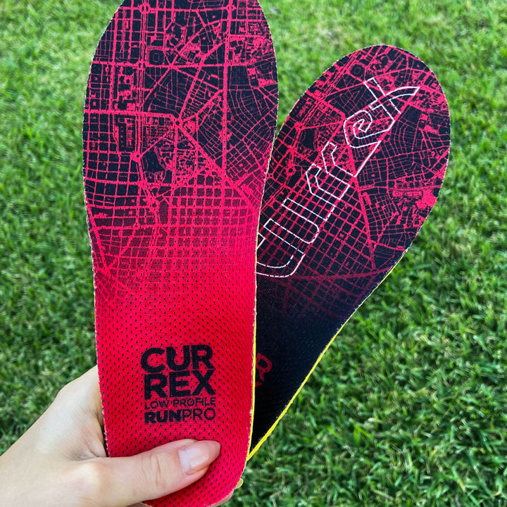 Woman holding up a pair of red low profile CURREX RUNPRO insoles #profile_low