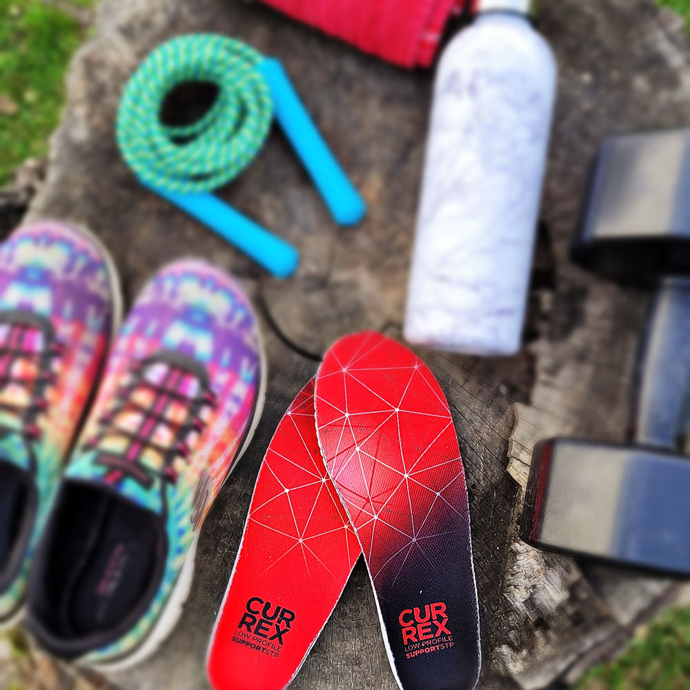 CURREX SUPPORTSTP red low profile insoles sitting on tree stump next to jump rope, water bottle, weight, and sneakers #profile_low